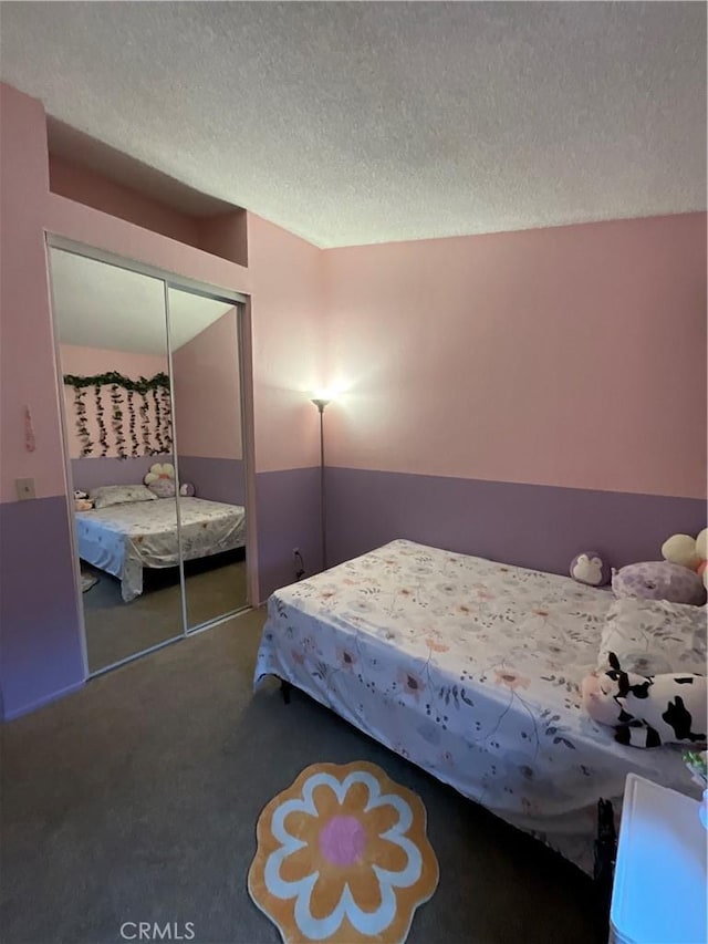 unfurnished bedroom featuring a closet, a textured ceiling, and dark colored carpet