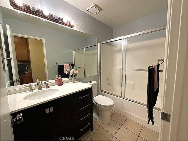 full bathroom featuring bath / shower combo with glass door, vanity, tile patterned floors, and toilet