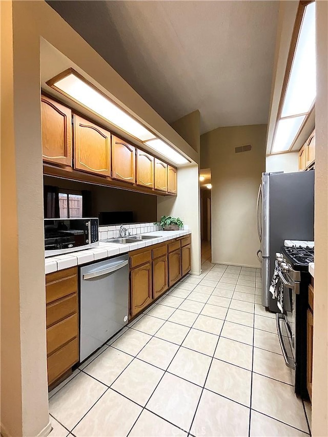 44009 17th St E, Lancaster, CA 93535 - kitchen featuring visible vents, a sink, tile counters, stainless steel appliances, and light tile patterned flooring