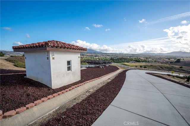 view of side of home with a mountain view and a storage unit