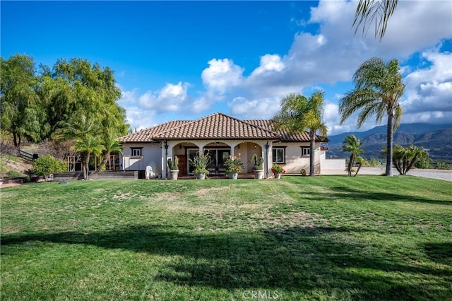 back of house with a mountain view and a lawn