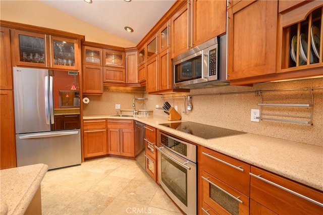 kitchen featuring lofted ceiling, sink, stainless steel appliances, tasteful backsplash, and light stone countertops