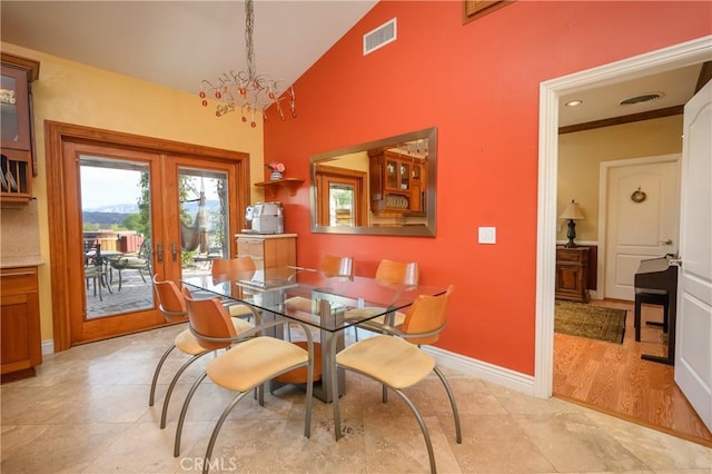 dining space with high vaulted ceiling, an inviting chandelier, and french doors