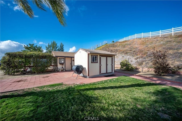 rear view of house with a yard, a patio area, and a shed