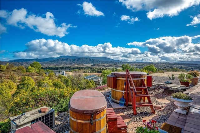 view of patio with a hot tub and a mountain view