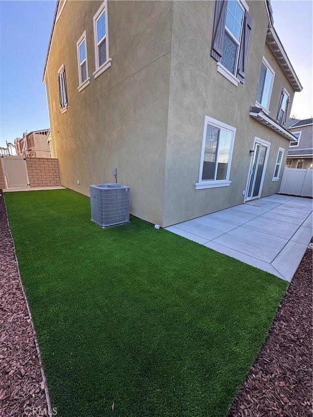 back of property with a yard, a patio, and central air condition unit