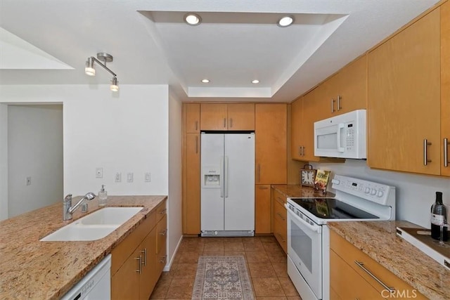 kitchen featuring white appliances, light stone counters, a raised ceiling, light tile patterned floors, and sink