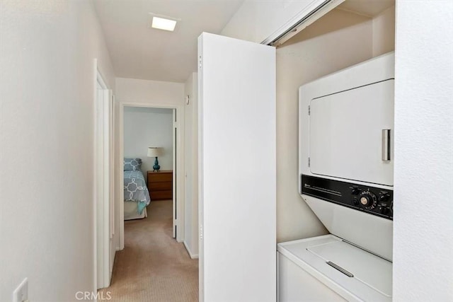 laundry area featuring stacked washer and dryer and light colored carpet