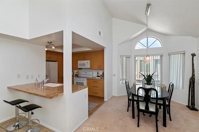 kitchen featuring sink, white appliances, high vaulted ceiling, and kitchen peninsula