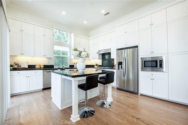 kitchen featuring a kitchen island, stainless steel appliances, a breakfast bar, and white cabinets