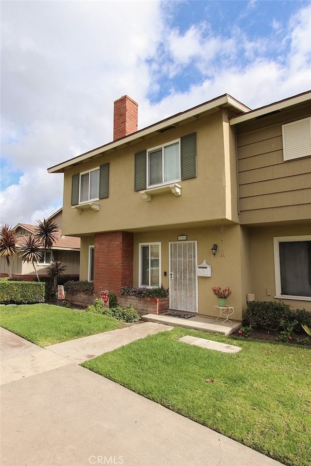 view of front of property with a front lawn, a chimney, and stucco siding