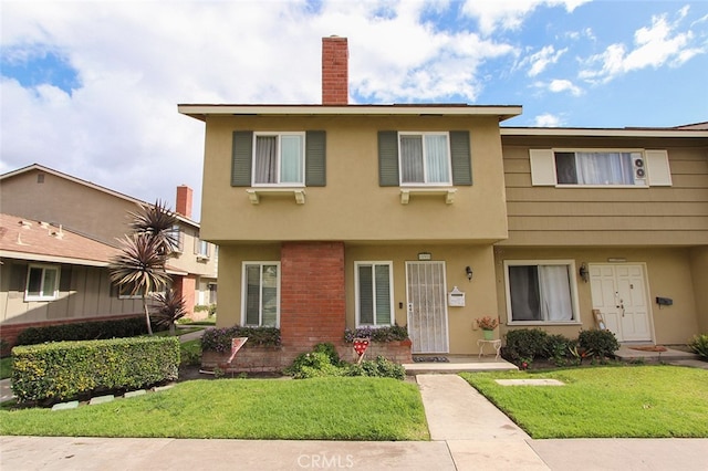 view of front of house featuring a chimney, a front lawn, and stucco siding