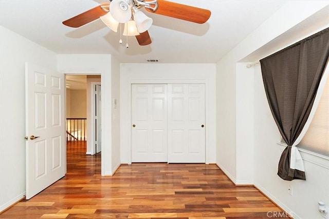 unfurnished bedroom featuring ceiling fan, light wood-type flooring, and a closet