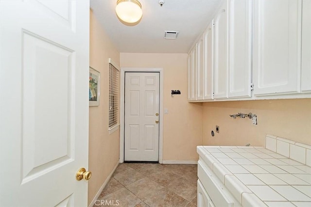 washroom featuring washer hookup, light tile patterned flooring, cabinets, and hookup for an electric dryer