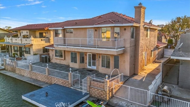 back of property with a water view and a patio