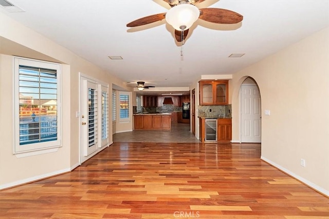 unfurnished living room featuring hardwood / wood-style flooring, wine cooler, and ceiling fan