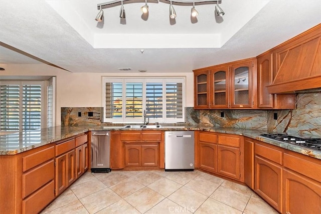 kitchen featuring appliances with stainless steel finishes, a tray ceiling, kitchen peninsula, and sink