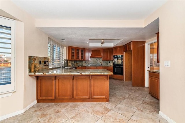 kitchen with sink, backsplash, kitchen peninsula, custom range hood, and black appliances