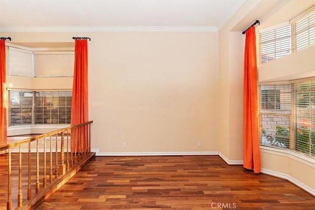 empty room with crown molding, plenty of natural light, and dark wood-type flooring