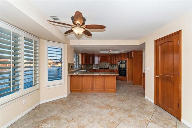 kitchen featuring double oven, sink, decorative backsplash, custom exhaust hood, and kitchen peninsula