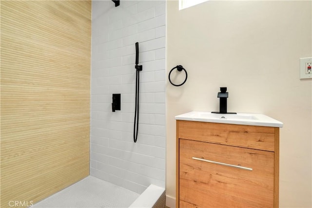 bathroom with tiled shower and vanity