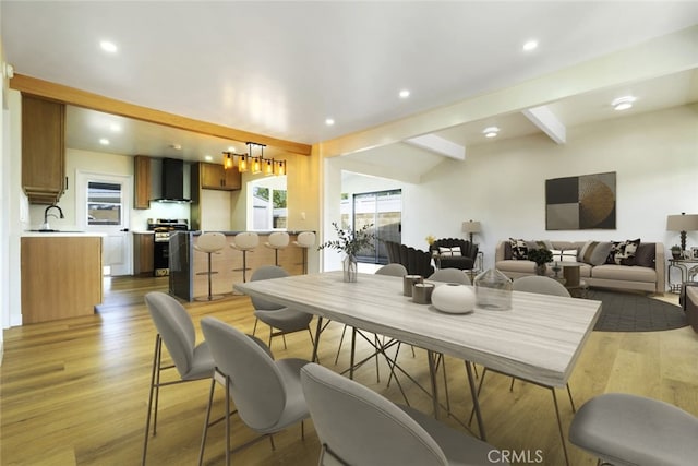 dining space featuring hardwood / wood-style flooring, beamed ceiling, and sink