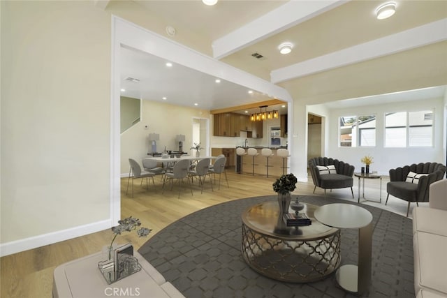 living room with a healthy amount of sunlight, wood-type flooring, and beamed ceiling