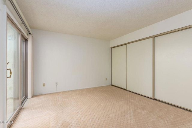 unfurnished bedroom featuring multiple windows, light colored carpet, a textured ceiling, and a closet