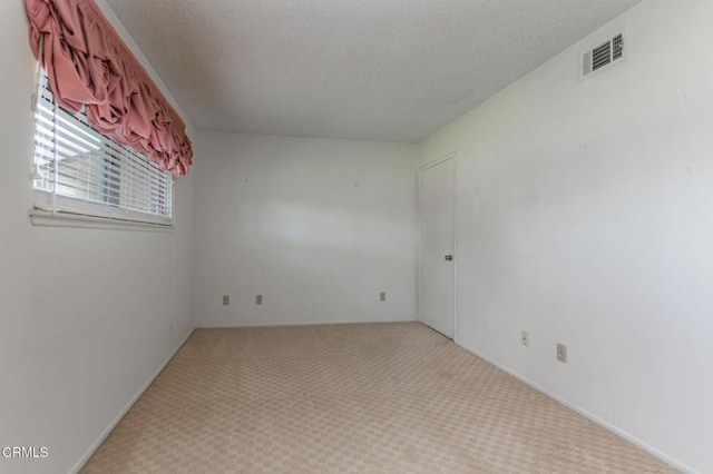 carpeted spare room featuring a textured ceiling