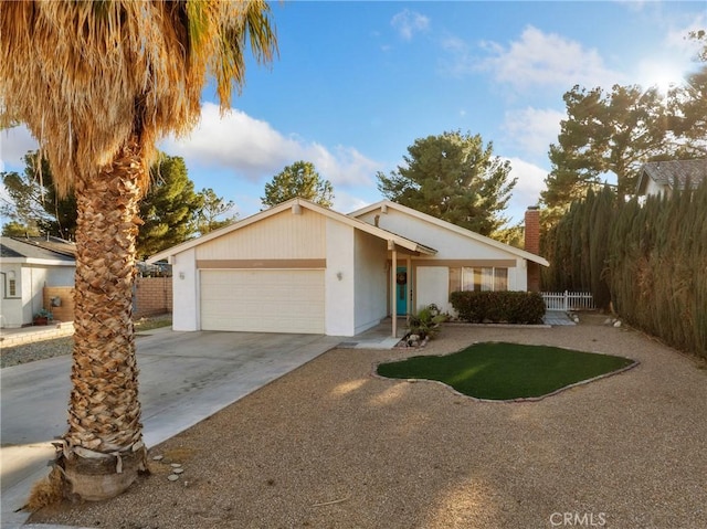 view of front of property featuring an attached garage, a chimney, fence, and concrete driveway