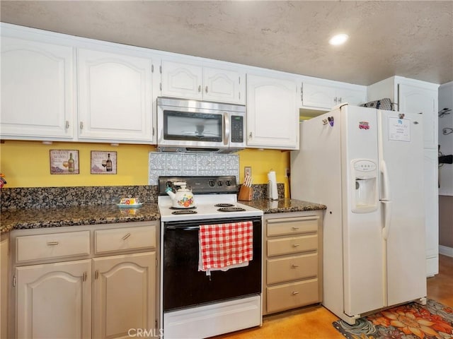 27767 Hummingbird Ln, Helendale, CA 92342 - kitchen featuring electric range, stainless steel microwave, white fridge with ice dispenser, white cabinetry, and dark stone counters