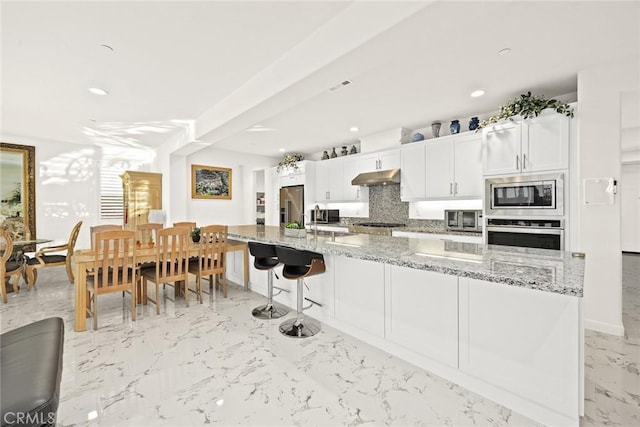 kitchen featuring stainless steel appliances, tasteful backsplash, light stone countertops, and white cabinets