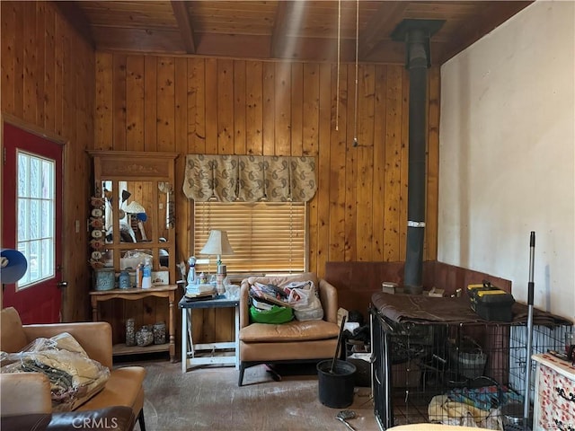 sitting room featuring wooden ceiling, wood walls, beamed ceiling, and a wood stove