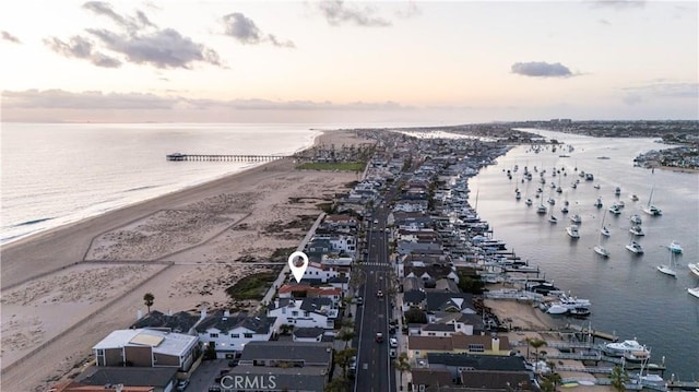 aerial view at dusk with a water view and a view of the beach