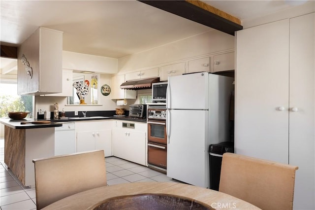 kitchen featuring light tile patterned flooring, sink, beamed ceiling, white appliances, and white cabinets