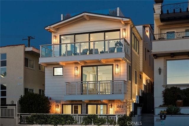 back of house featuring a balcony and a fenced front yard