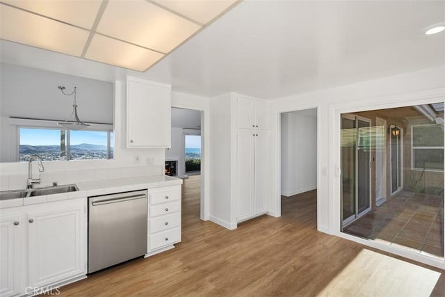 kitchen with tile counters, hanging light fixtures, white cabinets, a sink, and dishwasher