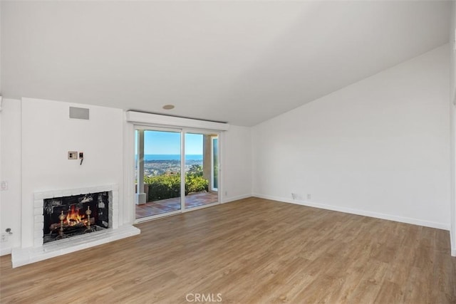 unfurnished living room with light wood-type flooring, a brick fireplace, visible vents, and baseboards