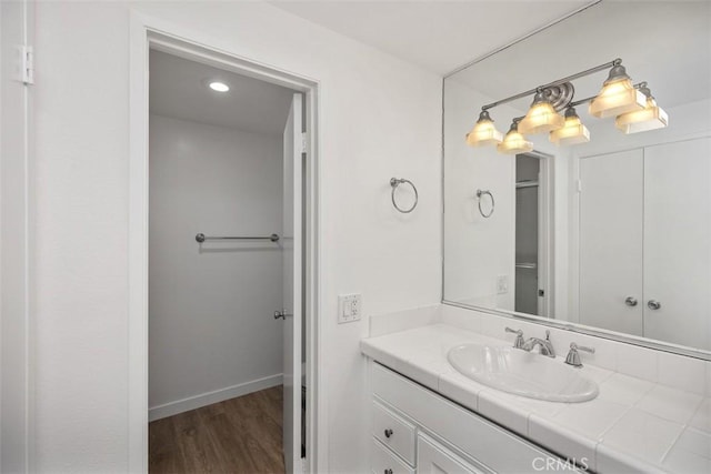 bathroom with wood finished floors, vanity, and baseboards