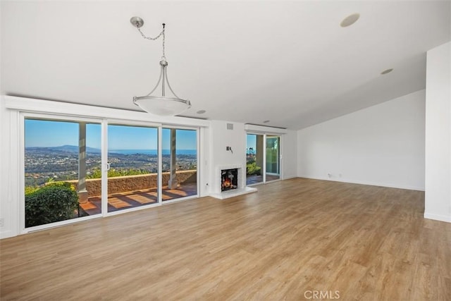 unfurnished living room featuring a mountain view, a lit fireplace, and light wood finished floors