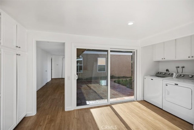 washroom featuring cabinet space, baseboards, wood finished floors, and washing machine and clothes dryer