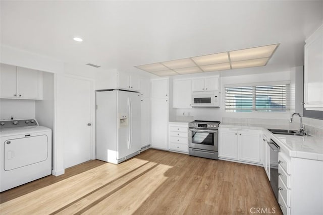 kitchen featuring washer / dryer, appliances with stainless steel finishes, light countertops, light wood-type flooring, and white cabinetry