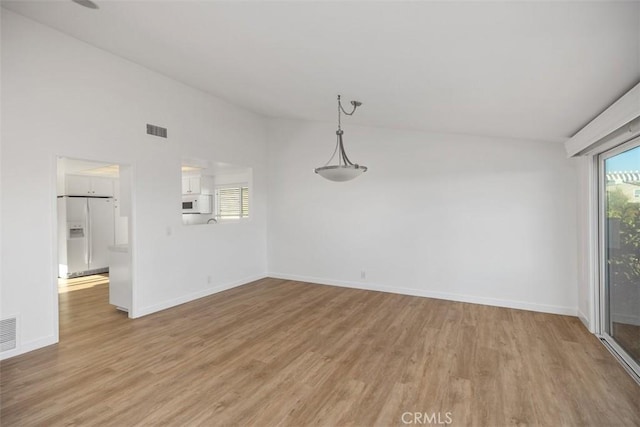 unfurnished dining area featuring lofted ceiling, light wood-style floors, baseboards, and visible vents