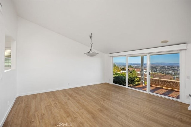 spare room featuring lofted ceiling, baseboards, and wood finished floors