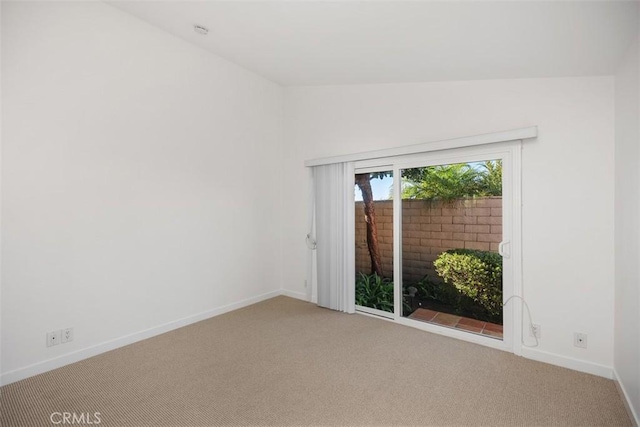 carpeted empty room featuring lofted ceiling and baseboards