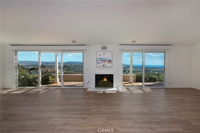 31232 Palma Dr, Laguna Niguel, CA 92677 - unfurnished living room featuring a lit fireplace, wood finished floors, a mountain view, and plenty of natural light