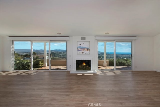 31232 Palma Dr, Laguna Niguel, CA 92677 - unfurnished living room featuring a warm lit fireplace, wood finished floors, a mountain view, and plenty of natural light