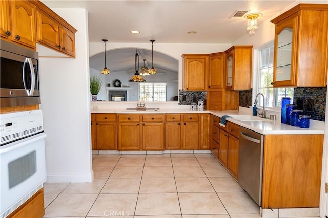 kitchen featuring sink, backsplash, hanging light fixtures, light tile patterned floors, and stainless steel appliances