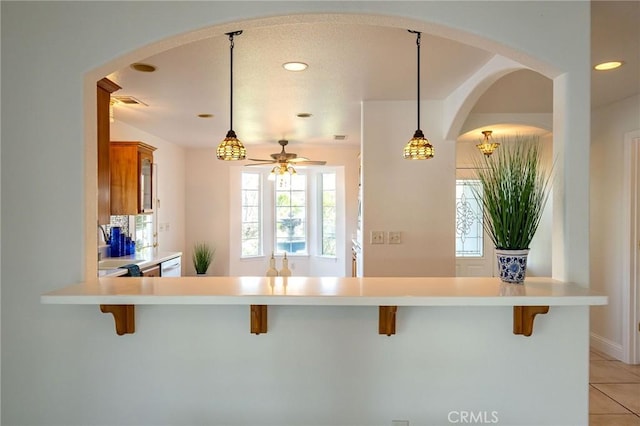 kitchen with hanging light fixtures, light tile patterned floors, a breakfast bar area, and ceiling fan