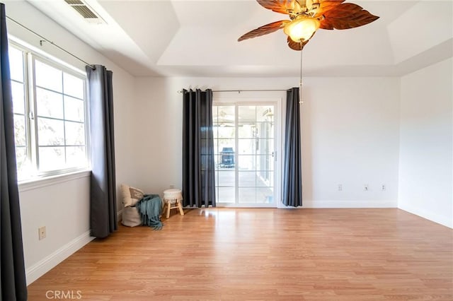 spare room featuring ceiling fan, a tray ceiling, and light wood-type flooring